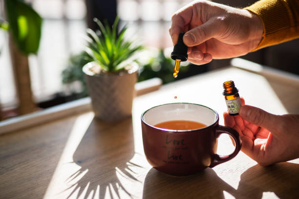 homem usando óleo cbd em seu chá. - tea cup tea cup herbal medicine - fotografias e filmes do acervo