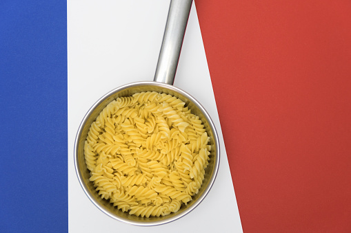 Pasta in saucepan on the white red blue background. Motive related to France