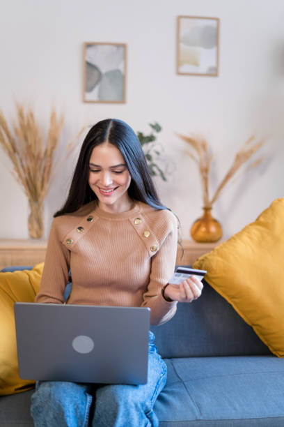 istock Smiling woman using laptop on sofa shopping online 1467462818