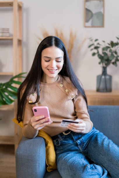 istock Smiling woman using smartphone at home shopping online 1467464363