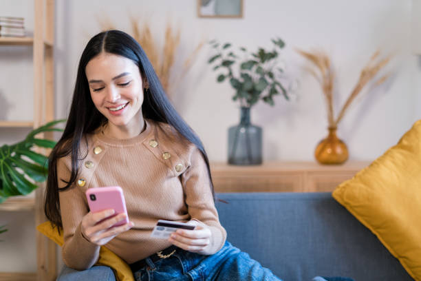 istock Smiling woman using smartphone at home shopping online 1467464462