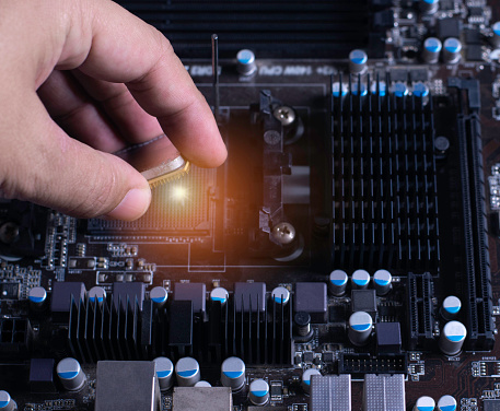 A technician is placing a CPU on the socket of a computer motherboard.