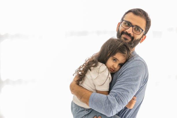 Father is holding his sad 3 year old daughter, consoling her