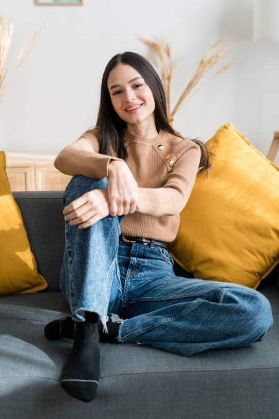 istock Smiling woman sitting on sofa looking at camera 1467468934