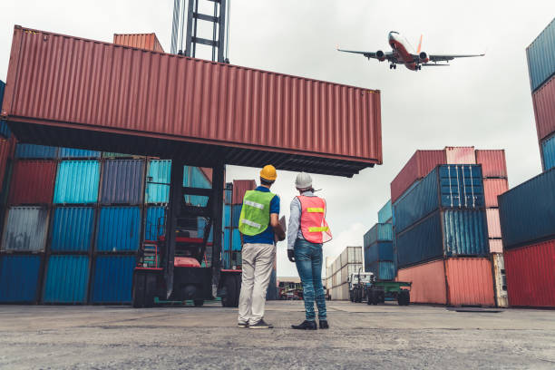 istock Industrial worker works with co-worker at overseas shipping container port . Logistics supply chain management and international goods export concept . 1467471871