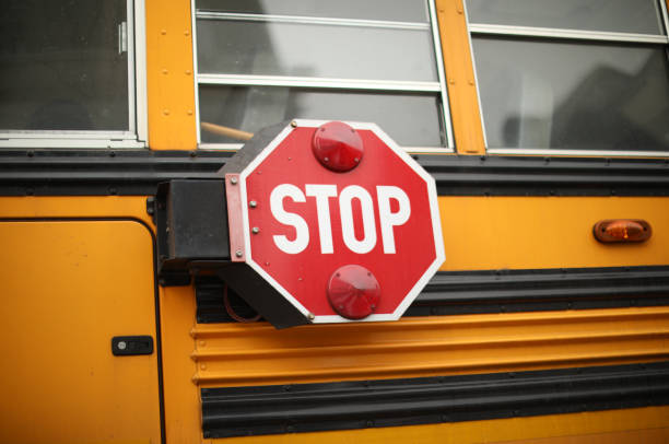 istock yellow school bus in public with stop sign showing 1467472946