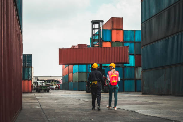 istock Industrial worker works with co-worker at overseas shipping container yard . Logistics supply chain management and international goods export concept . 1467480805