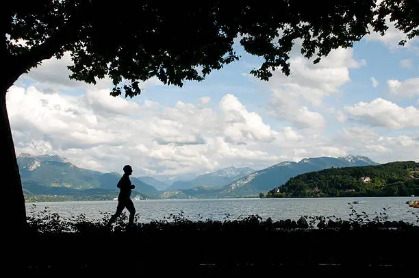 Man running around a lake.Alps on a background