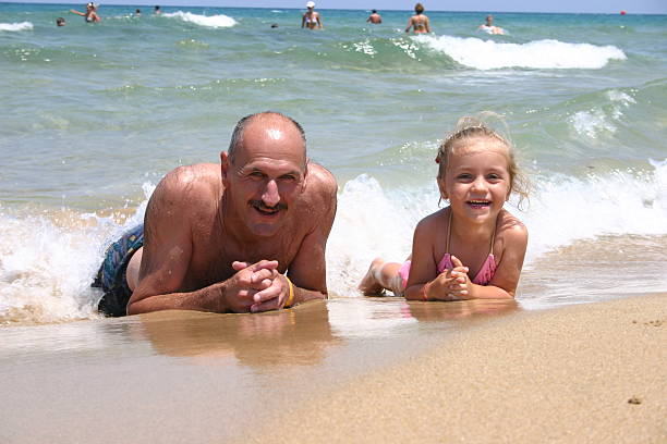 Girl and grandpa on the beach stock photo