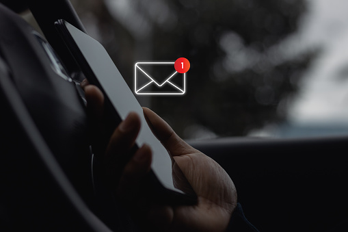 Close-up of Driver's hand use smartphone in site car with 1 new email notification alert icon pop up. Online communication business technology concept. Contact us by newsletter email, Email marketing.