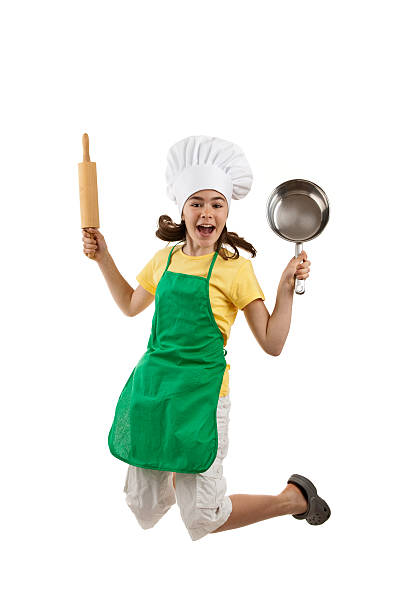 Happy young chef in green apron jumping joyfully and smiling