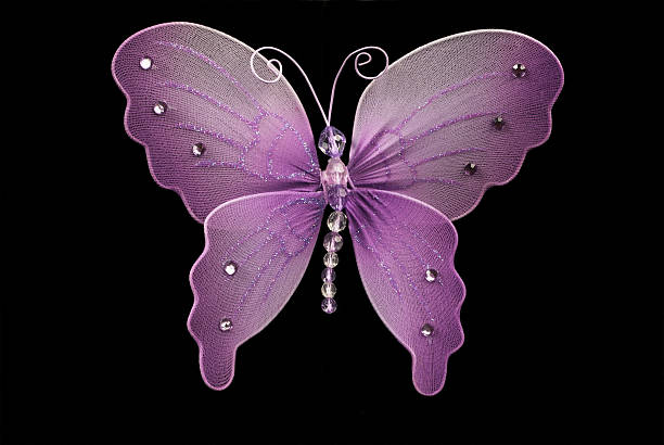 This is a purple toy butterfly made with fabric and pearls over a black background.