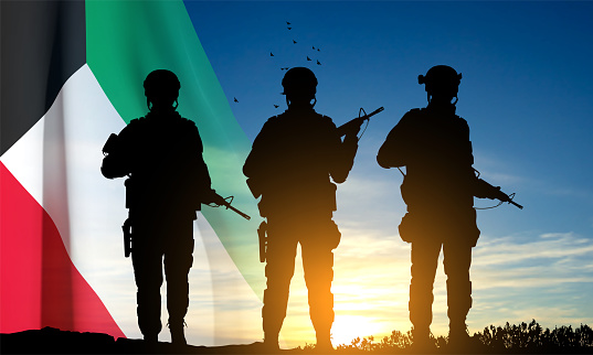 Kuwait flag and the silhouettes of a soldiers on background of sunset. Concept - National, Liberation Days. EPS10 vector