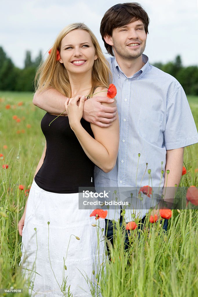 Happy couple standing in poppy filed Cheerful Stock Photo