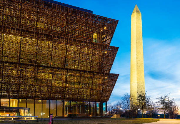 The National Museum of African American History and Culture Washington D.C., USA - February 10, 2023: The National Museum of African American History and Culture at night with the Washington Monument in downtown Washington DC. smithsonian museums stock pictures, royalty-free photos & images