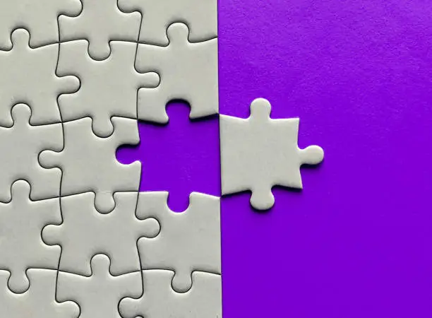 Top view of missing jigsaw puzzle with customizable space for text on maroon color background. Copy space.