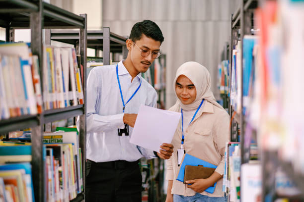 istock Asian teachers standing in library and discussing about their plan. 1467504949