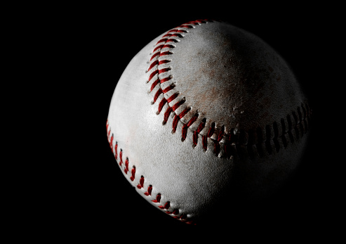 A well used baseball from a professional sports game isolated on a black background.  