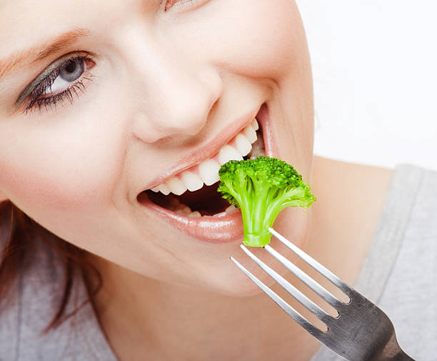 istock Young woman eating broccoli off a fork 146751308