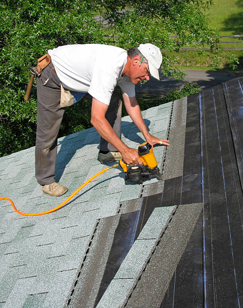 Man attaches shingles to roof stock photo