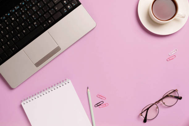 istock Office desk with blank notepad computer supplies coffee cup pink background. Finance office business 1467525236
