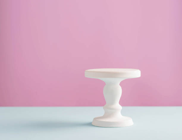 Empty white stand for a birthday cake on a pink plain background