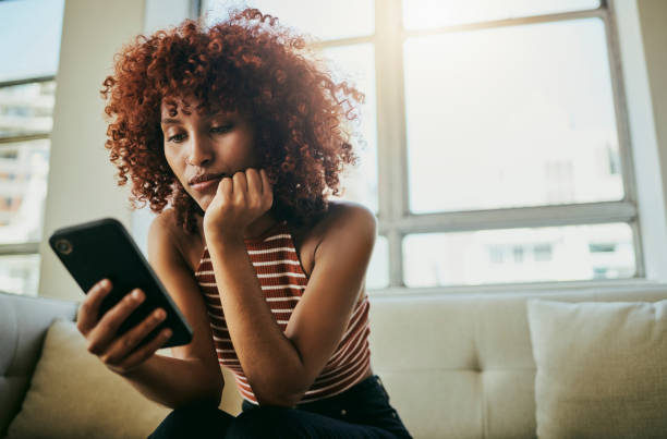 istock Woman, phone and home sofa while online for communication on social media mobile app chat. Bored person with smartphone typing email, blog post or search on internet waiting on slow wifi connection 1467526225