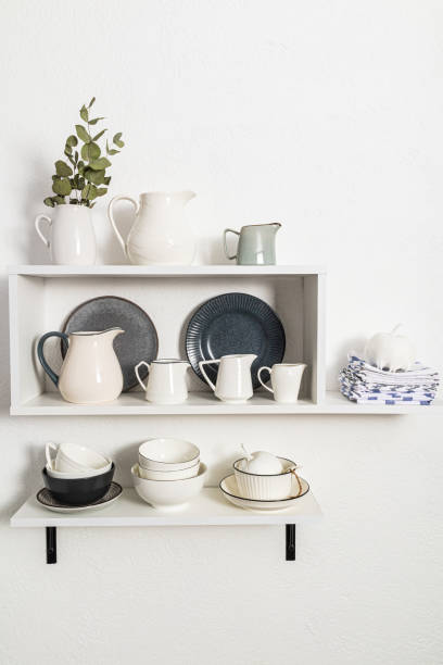 istock various cookware on open white shelves on a white stylish wall. vertical view. decorative items in the interior of the kitchen. 1467531500