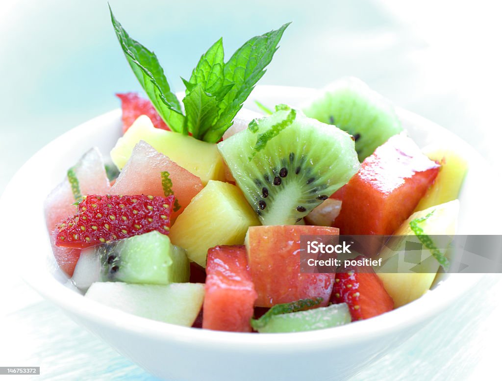 bowl of fruit salad on blue healthy and deliciously looking bowl of fruit salad on blue background Apple - Fruit Stock Photo