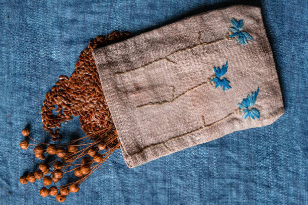 istock Flax seeds. Seed pods. Small canvas bag for seeds. Blue linen fabric background. 1467534796