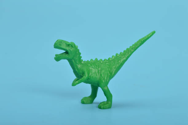istock Green T-Rex dinosaur toy isolated on a blue background 1467539312
