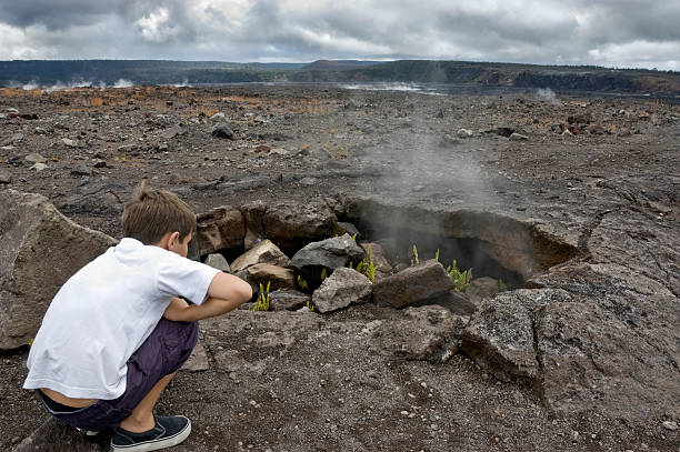 istock Boy watching steam coming out of lava hole. 146754326