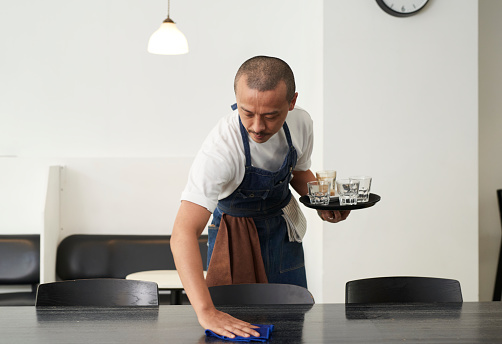Waiter cleaning a table at a coffee shop.