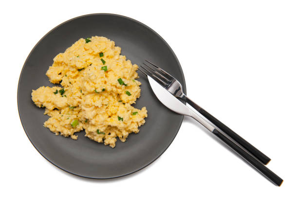 rührei mit frischem grünem schnittlauch auf dunkelgrauem teller mit elegantem besteck isoliert auf weißem hintergrund - fork plate isolated scrambled eggs stock-fotos und bilder