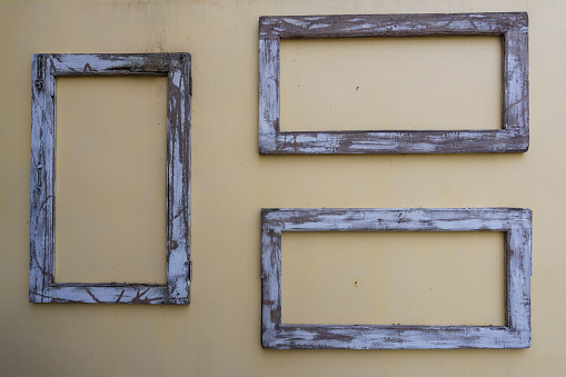 Three old wooden frames on stucco wall, close up