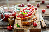 Sandwich with jam made of cherries in summer garden.