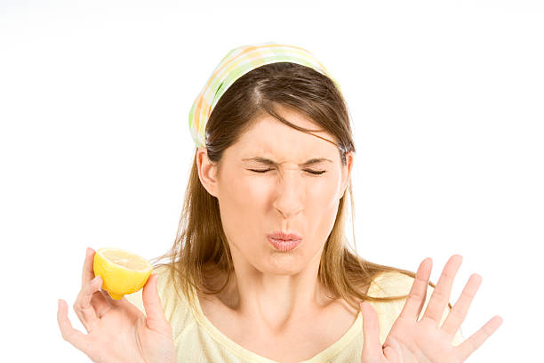 Young woman sour grimace with half of lemon stock photo