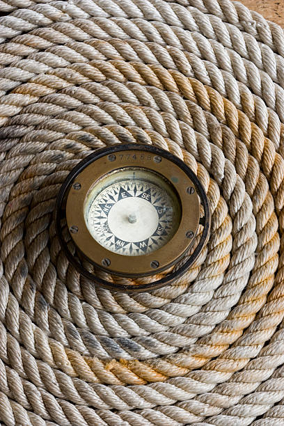 Coiled marine anchor line with antique compass stock photo