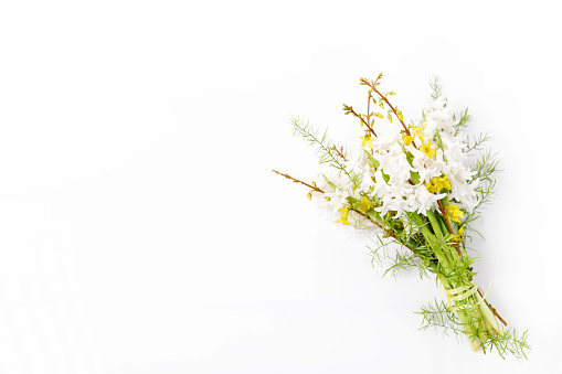 Tied bouquet of spring flowers on a white background, white hyacinths and greenery