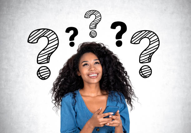 istock Smiling african young woman with phone and question marks on wall 1467560757