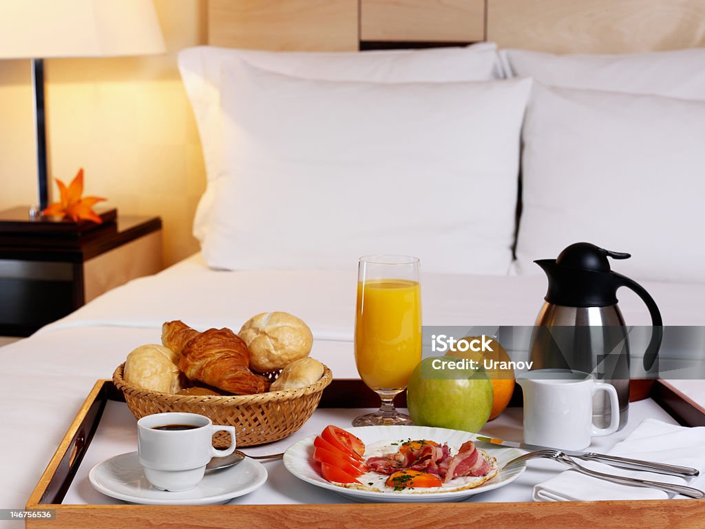A serving tray with a rich breakfast on a bed Tray with breakfast on a bed in a hotel room Apple - Fruit Stock Photo