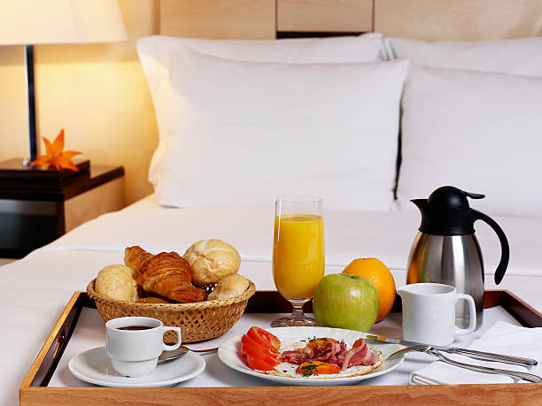 A serving tray with a rich breakfast on a bed stock photo