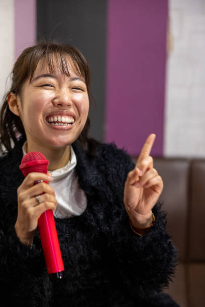 istock Young woman singing karaoke - looking at camera 1467565430