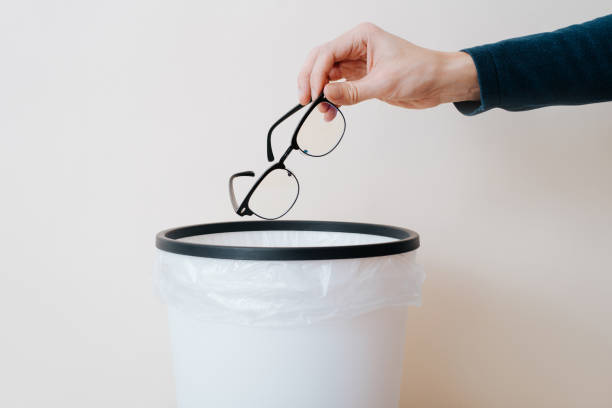 istock Close-up of hand throwing out eyeglasses into trash can 1467565853