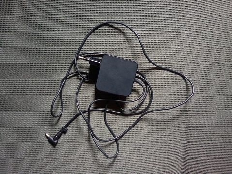 Laptop charger with its messy cable on a structured surface