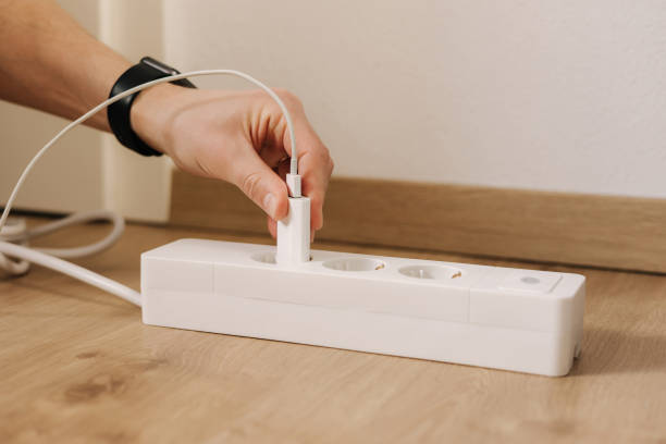 istock Human hand puts the charger into the extension cord. White cable connector 1467572329