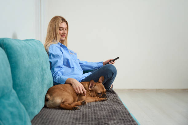 istock Loving master petting her dog while changing channels on TV 1467572980
