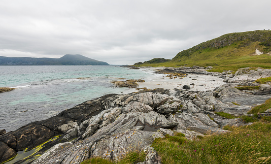 Coastal hiking trail with rocks  and a cloudy sky during summer on Godøy island, Møre og Romsdal, Norway