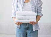 Woman holds stack clean white towels in her hands. Concept of cleaning washing and cleanliness