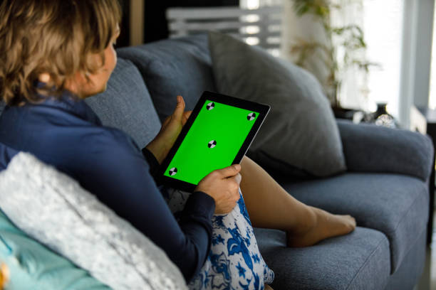 istock Woman lounging on the sofa and using digital tablet with chroma key on the screen 1467575961
